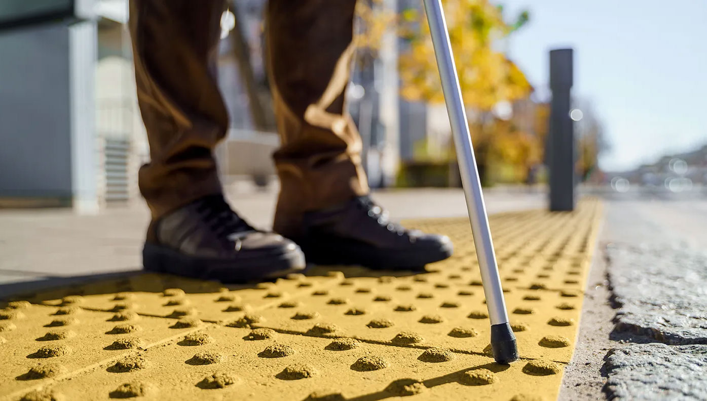 SS4A-Funding-new Close-up of person using a white cane on tactile paving for accessible navigation